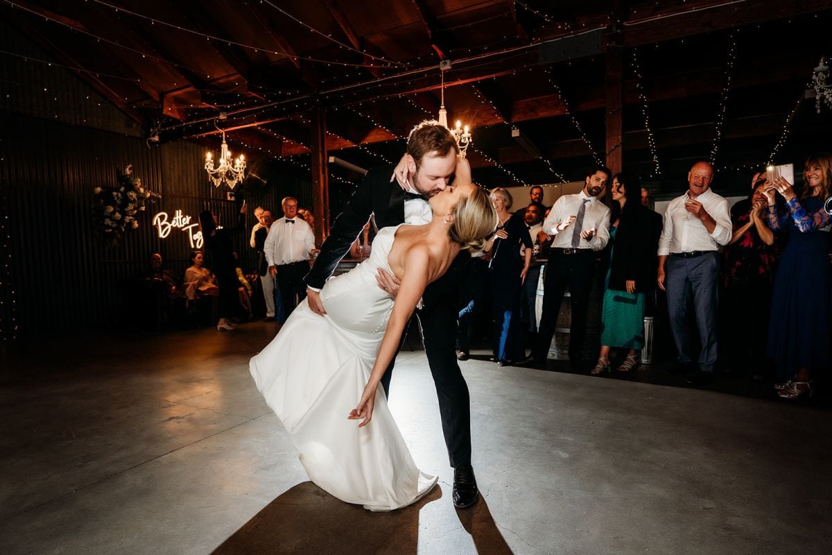 Patrick dipping Eileen for a kiss on the wedding dance floor as their guests watch and applaud.