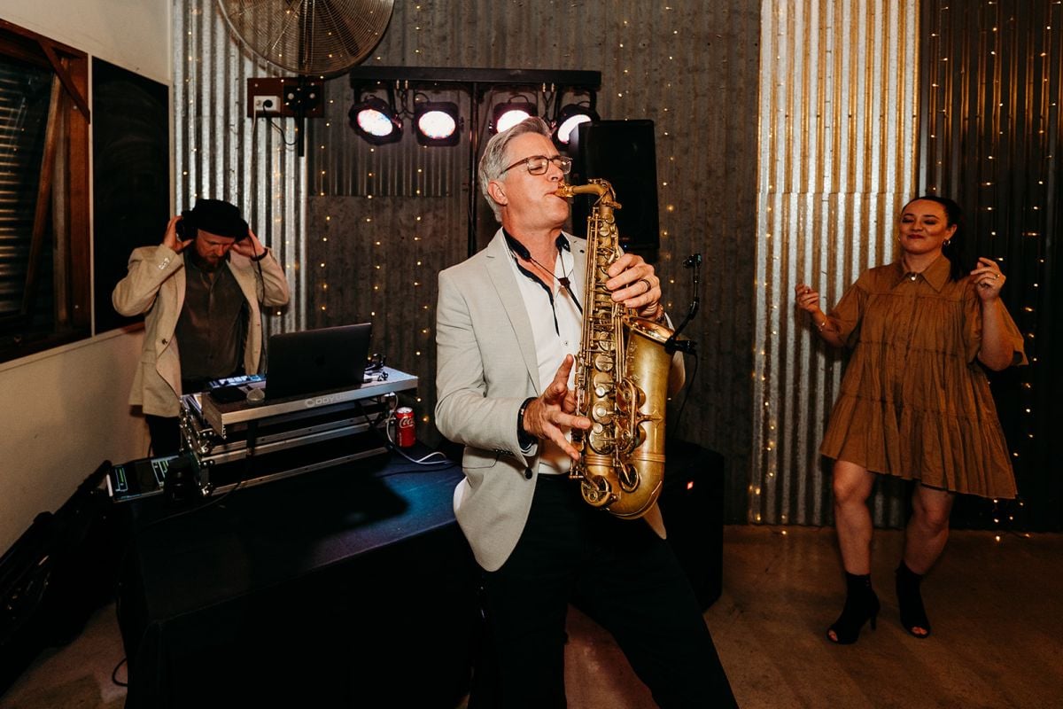 Duke Music saxophonist performing in front of the DJ decks, with the vocalist dancing beside him at the wedding reception.