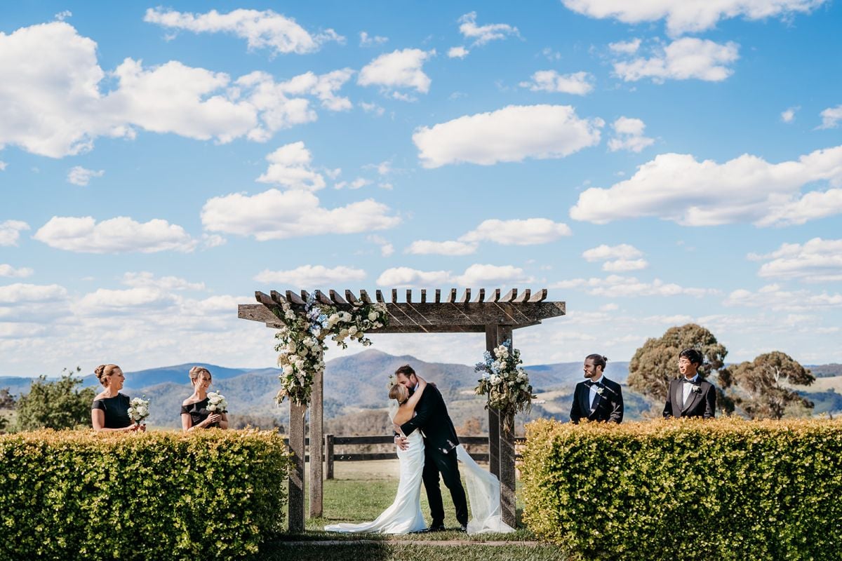 Bride and Groom underneath wedding arbour kissing at Seclusions